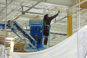 worker spray painting metal ceiling trusses at a Pickering, ON plant