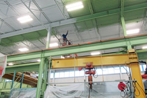 Toronto spray painter working on steel beams and metal ceiling in a factory