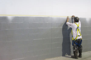 Brantford painter masking and spray painting a commercial building wall