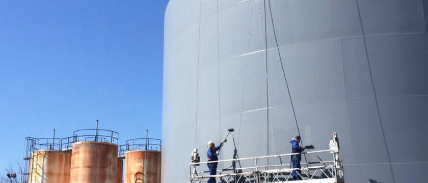 industrial painters spray painting a steel storage tank