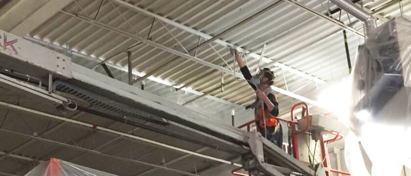 commercial painter spray painting a metal ceiling