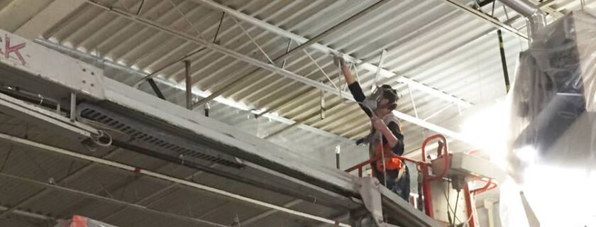 commercial painter spray painting a metal ceiling