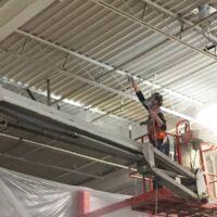 commercial painter spray painting a metal ceiling
